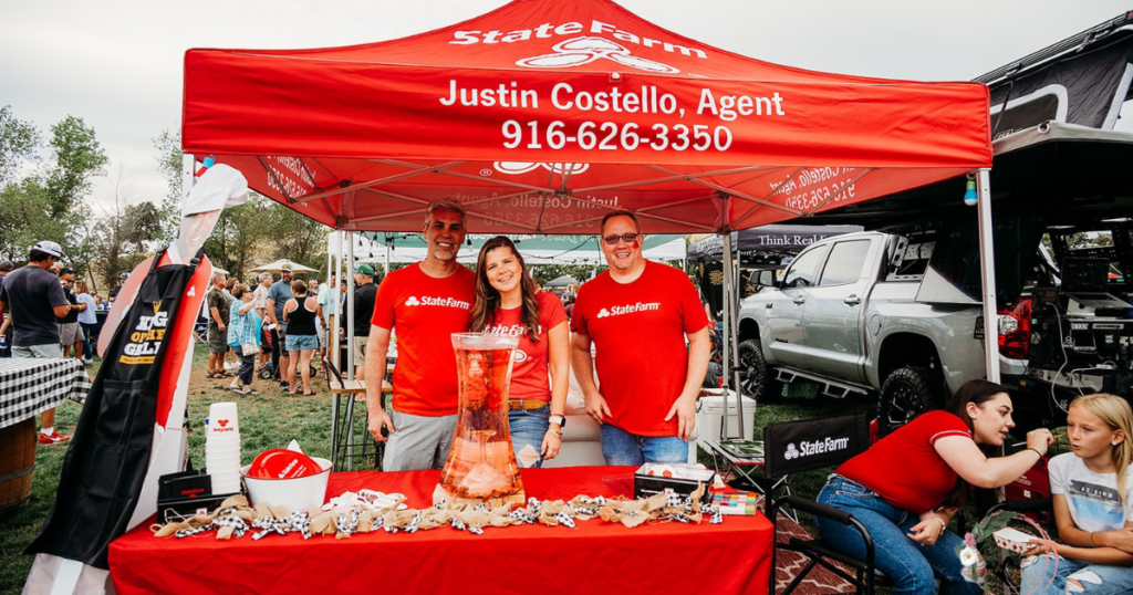 A picture of Justin Costello and his team in a red State Farm insurance tent at the 2022 12 Bridges Rib Cook-Off Competition.
