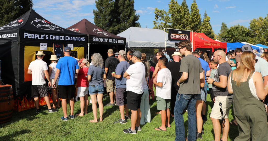 Attendees enjoying ribs while in line for rib cook-off teams at the 12 Bridges Rib Cook-Off in Lincoln CA.